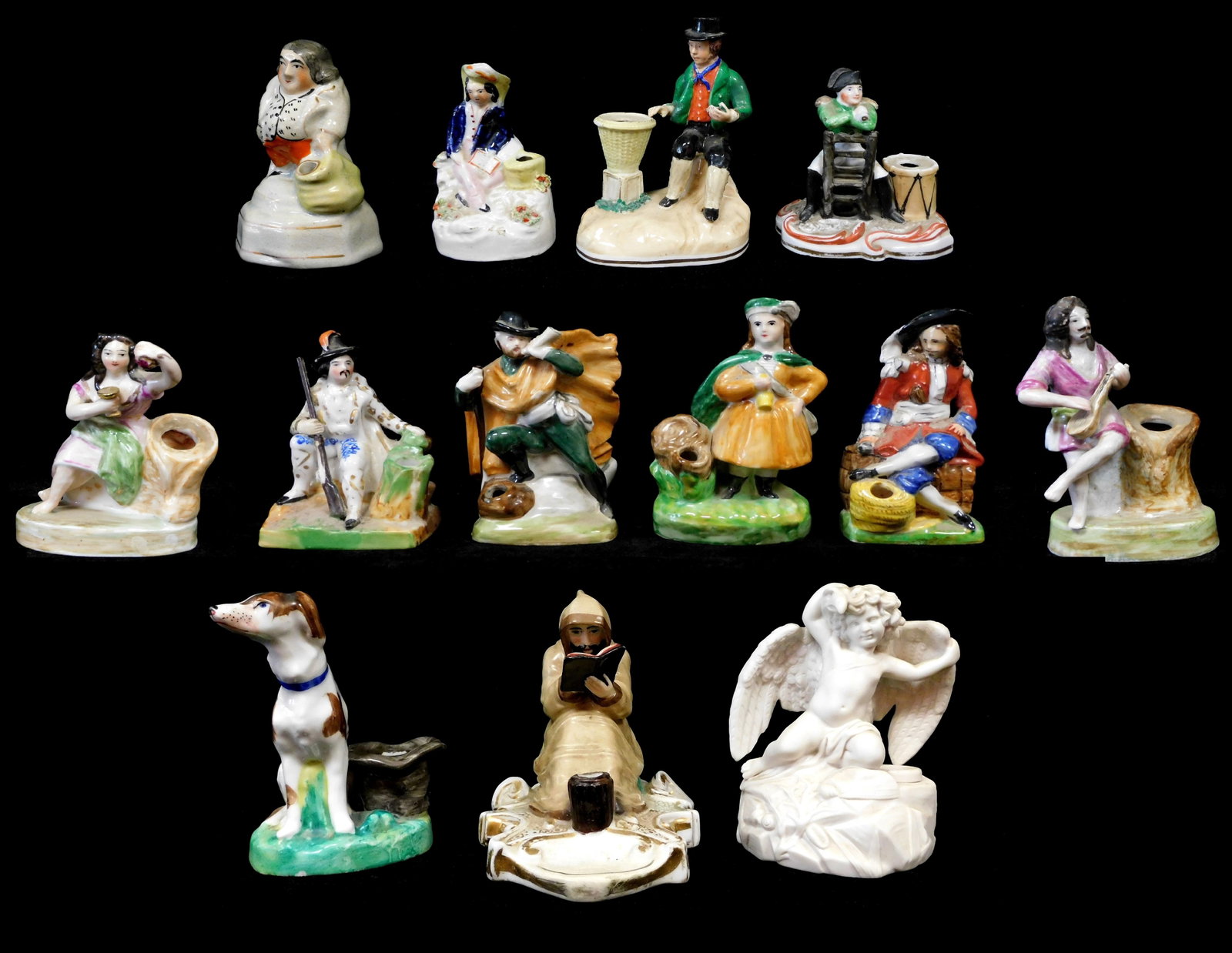 Thirteen figural inkwells, mostly Staffordshire, highlights include: dog with hat; man with musket: Thirteen figural inkwells, mostly Staffordshire, highlights include: dog with hat; man with musket resting next to a tree stump; scribe reading a book; many of figures next to inkwell form baskets; ma