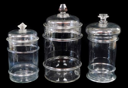GLASS: Three hand-blown clear glass apothecary jars, 20th C., pontil marks on base, domed lides with