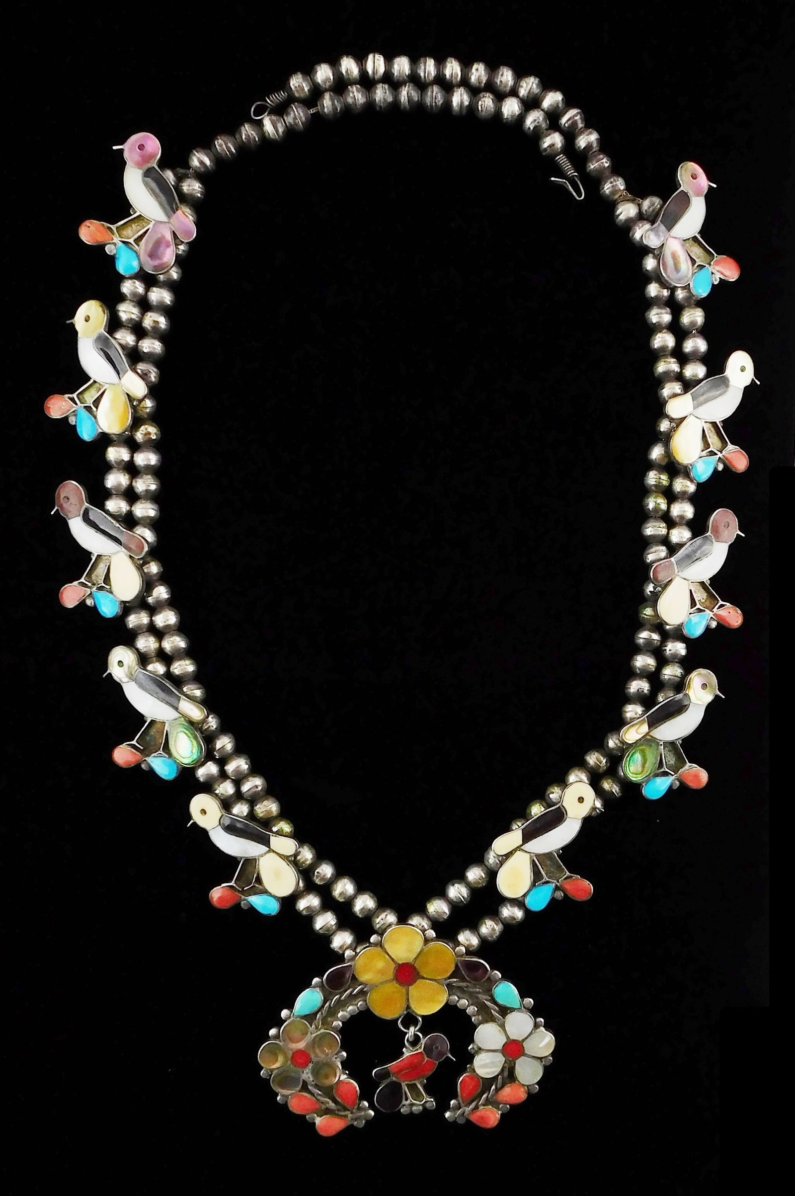 JEWELRY: Zuni style bird squash blossom necklace, enamel and stone veneer, tested silver, a single: JEWELRY: Zuni style bird squash blossom necklace, enamel and stone veneer, tested silver, a single row of ball beads lead to a double row, interspersed by ten bird charms inlaid with mother of pearl, 