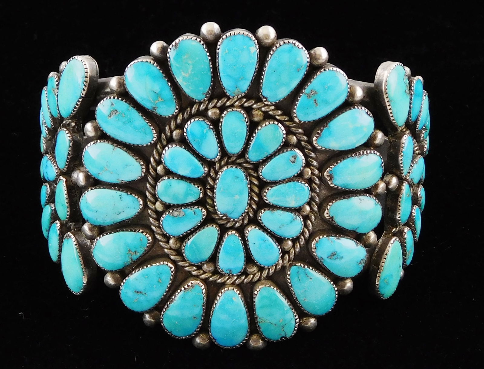 JEWELRY: Large Zuni cuff by Alice Quam with flower form center design and demilune sides, signed (1 of 5)