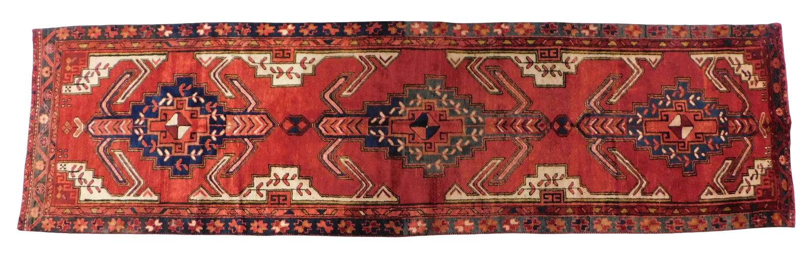 RUG: Heriz runner, 3' x 12', wool on cotton, classic tribal motifs, creams, reds and blues on a red (1 of 2)
