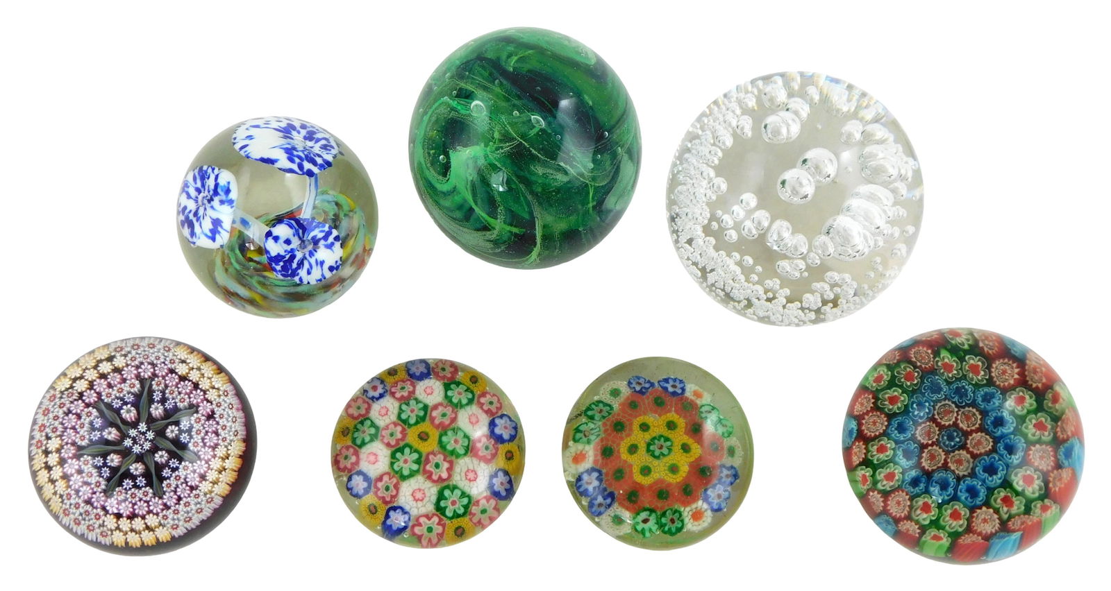 ART GLASS: Seven glass paperweights: four round clear with millefiori; one with three trumpets in: ART GLASS: Seven glass paperweights: four round clear with millefiori; one with three trumpets in blue and white; one green swirl and one clear with bubble design, all with wear consistent with age an