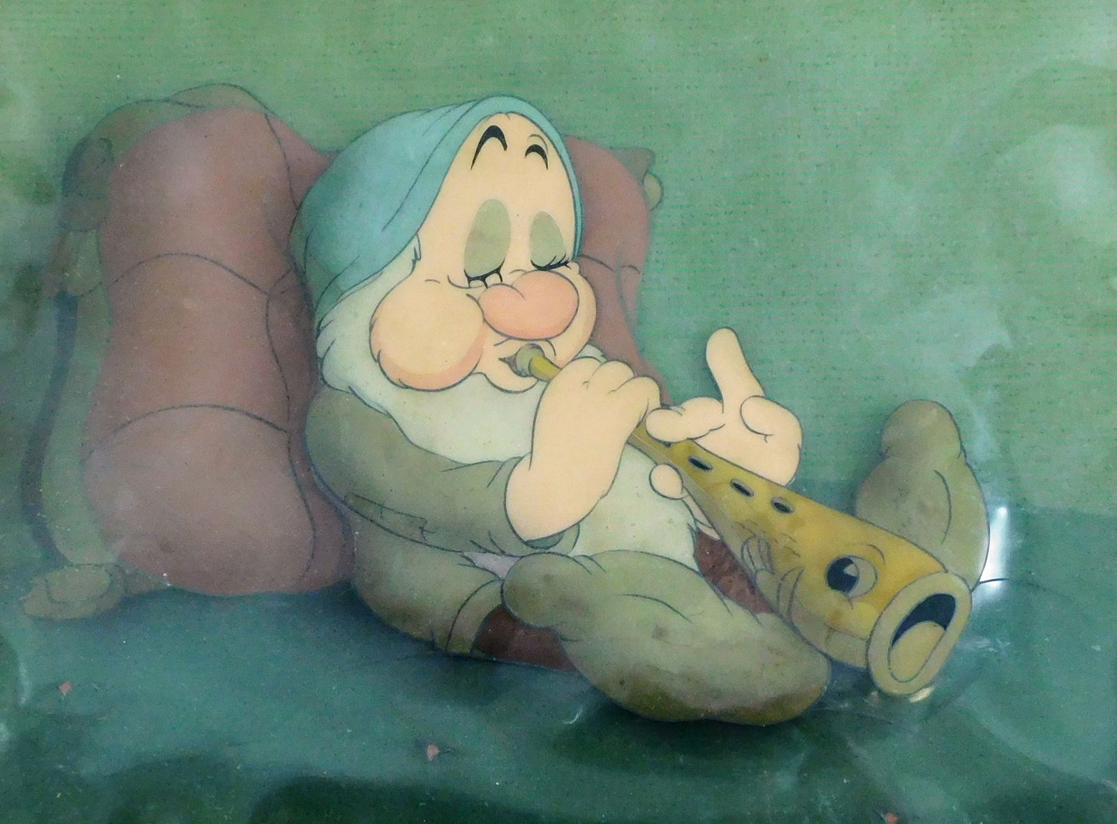 Original Disney "Sleepy" Production cel from "Snow White and the Seven Dwarfs", Disney Studios: Original Disney "Sleepy" Production cel from "Snow White and the Seven Dwarfs", Disney Studios (1937), gouache on trimmed celluloid, scene depicts "Sleepy" seated playing a flute or recorder while
