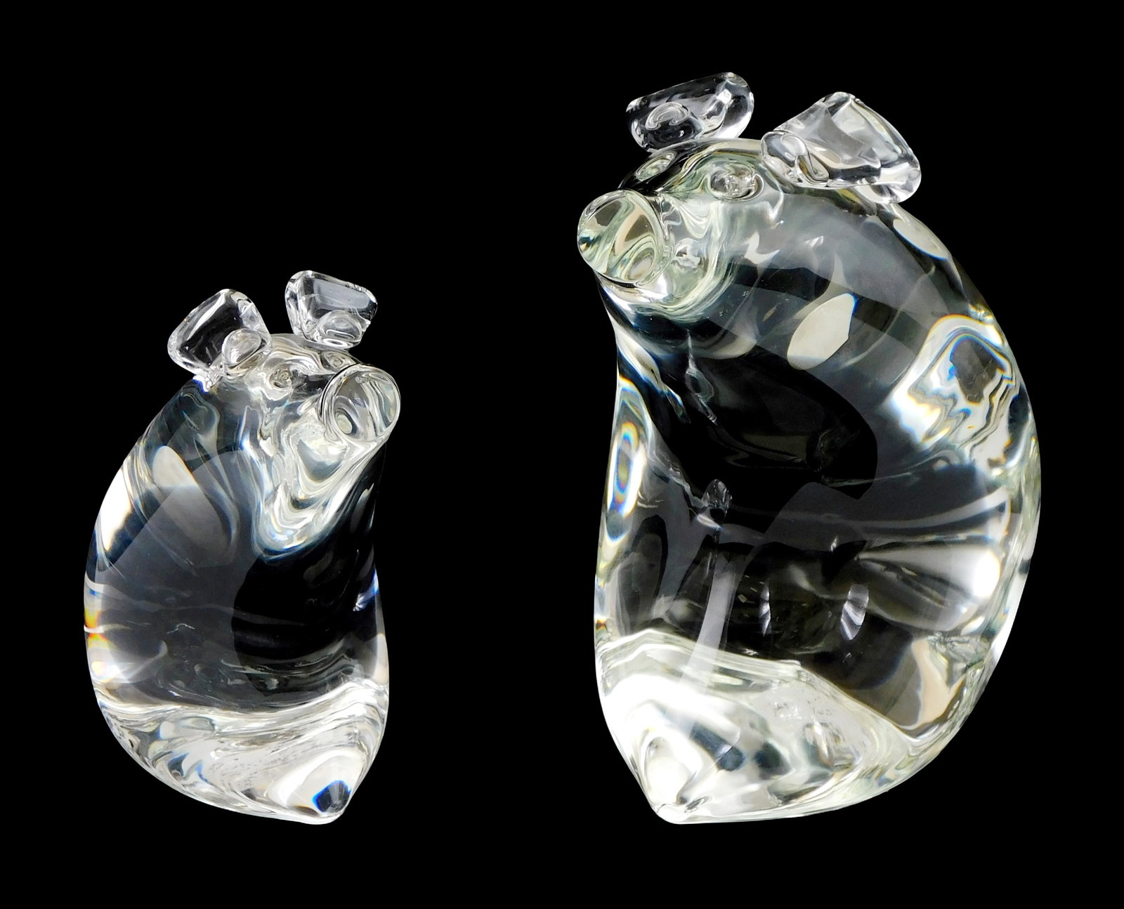 ART GLASS: Pair of Steuben crystal pigs, 1970s, designed by Lloyd Atkins, larger signed on base with: ART GLASS: Pair of Steuben crystal pigs, 1970s, designed by Lloyd Atkins, larger signed on base with “LDA”, both same design with one larger than the other, large: 6” h.; small: 4”