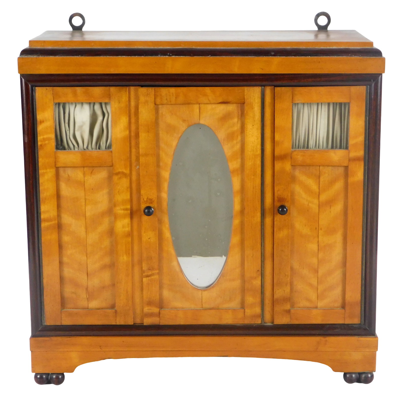 Biedermeier style diminutive wardrobe, tiger maple veneer, three panel front, central door with oval: Biedermeier style diminutive wardrobe, tiger maple veneer, three panel front, central door with oval mirror, flanking doors with inset windows, over ball feet, wear consistent with age, surface wear,