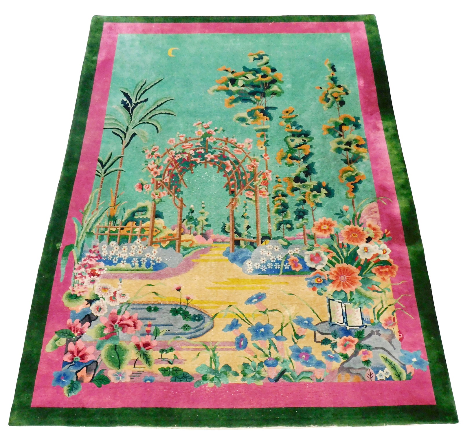RUG: Chinese Art Deco carpet, 13' 5" x 9' 8", c. 1930's, wool on cotton, garden scene with arched: RUG: Chinese Art Deco carpet, 13' 5" x 9' 8", c. 1930's, wool on cotton, garden scene with arched trellis and pond in foreground, vibrant magenta and green double border, wear consistent with age and 