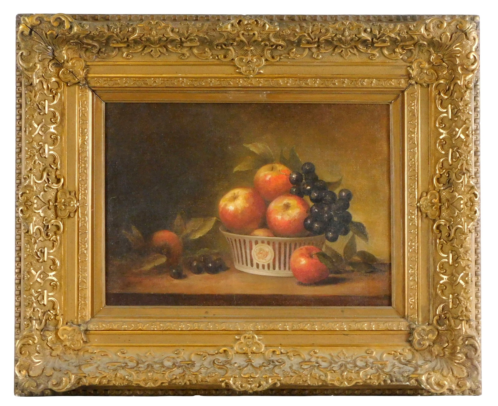 19th-Early 20th C. fruit still life, oil on canvas, white reticulated basket perched on table-top: 19th-Early 20th C. fruit still life, oil on canvas, white reticulated basket perched on table-top overflowing with apples and purple grapes, unsigned, ornate gilt frame, verso with faint stamp "The...