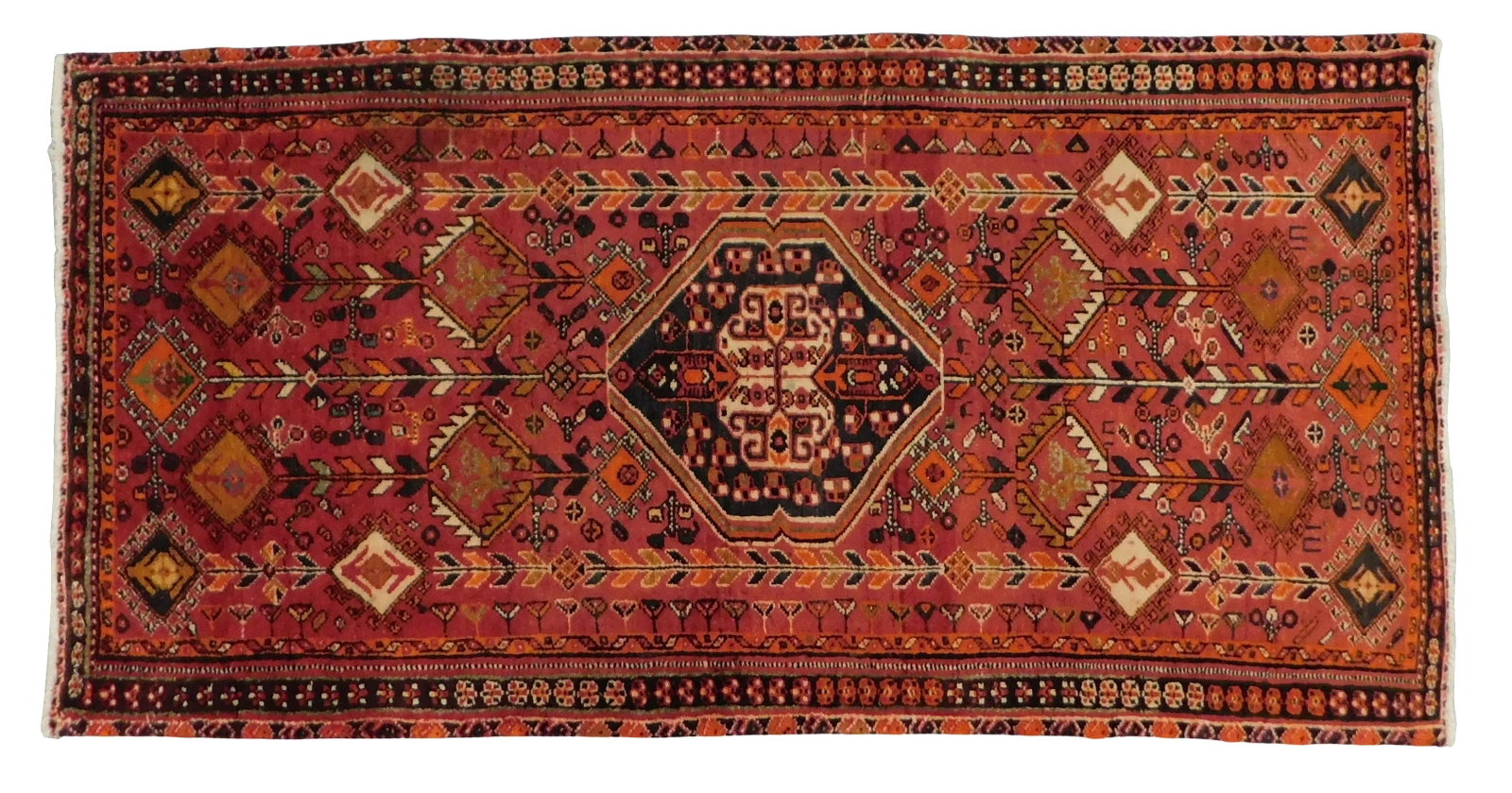 RUG: Quashqai, 2' 5" x 5' 1", wool on cotton, red ground, orange and black borders, central: RUG: Quashqai, 2' 5" x 5' 1", wool on cotton, red ground, orange and black borders, central medallion, repeating geometrical patterns throughout, wear consistent with age and use.