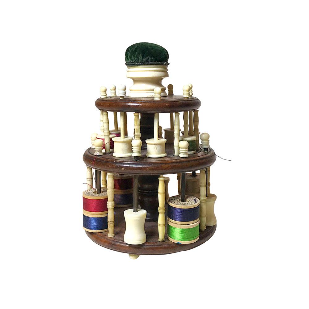 Turned Mahogany and Bone Spool Holder with Pin Cushion: Two tier mahogany and bone spool holder of circular form, the tiers supported on turned bone uprights. The lower tier uprights centering metal rods for thread spools, the upper tier uprights centering