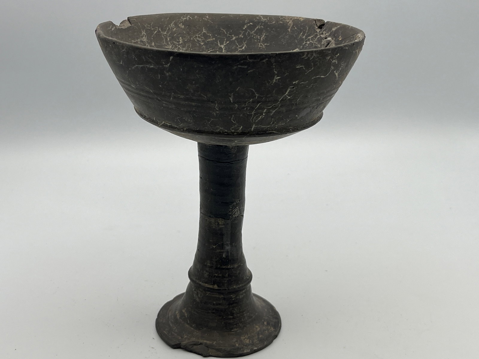 Etruscan Bucchero Pottery Long Stem Chalice: Classical World, Etruria, ca. early 6th century CE. An elegant chalice with a slightly concave bowl and flaring, trumpet-shaped foot with a short, hollow stem. In the interior of the bowl there is a d
