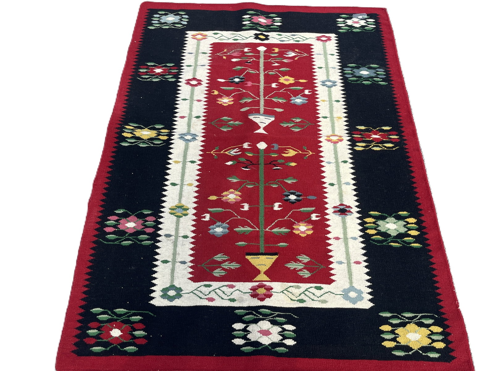 Mid‑Century Balkan Wool Kilim Rug, Tree‑of‑Life Motif, 46" × 66": A hand‑woven Balkan wool kilim rug, likely Serbian or Bulgarian, featuring a striking Tree‑of‑Life design on a deep red field framed by a cream zigzag border and dark outer band with