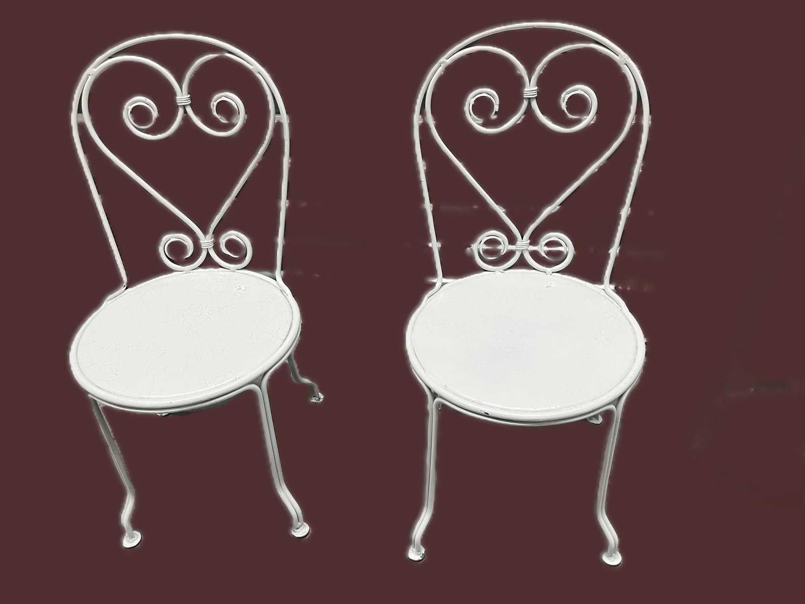 Pair of Vintage White Wrought Iron Children’s Chairs — Heart‑Back Ice Cream Parlor: A pair of vintage wrought iron children’s chairs featuring heart‑shaped scroll backs and round seats in a crisp white painted finish. The design evokes classic ice cream parlor or garden f