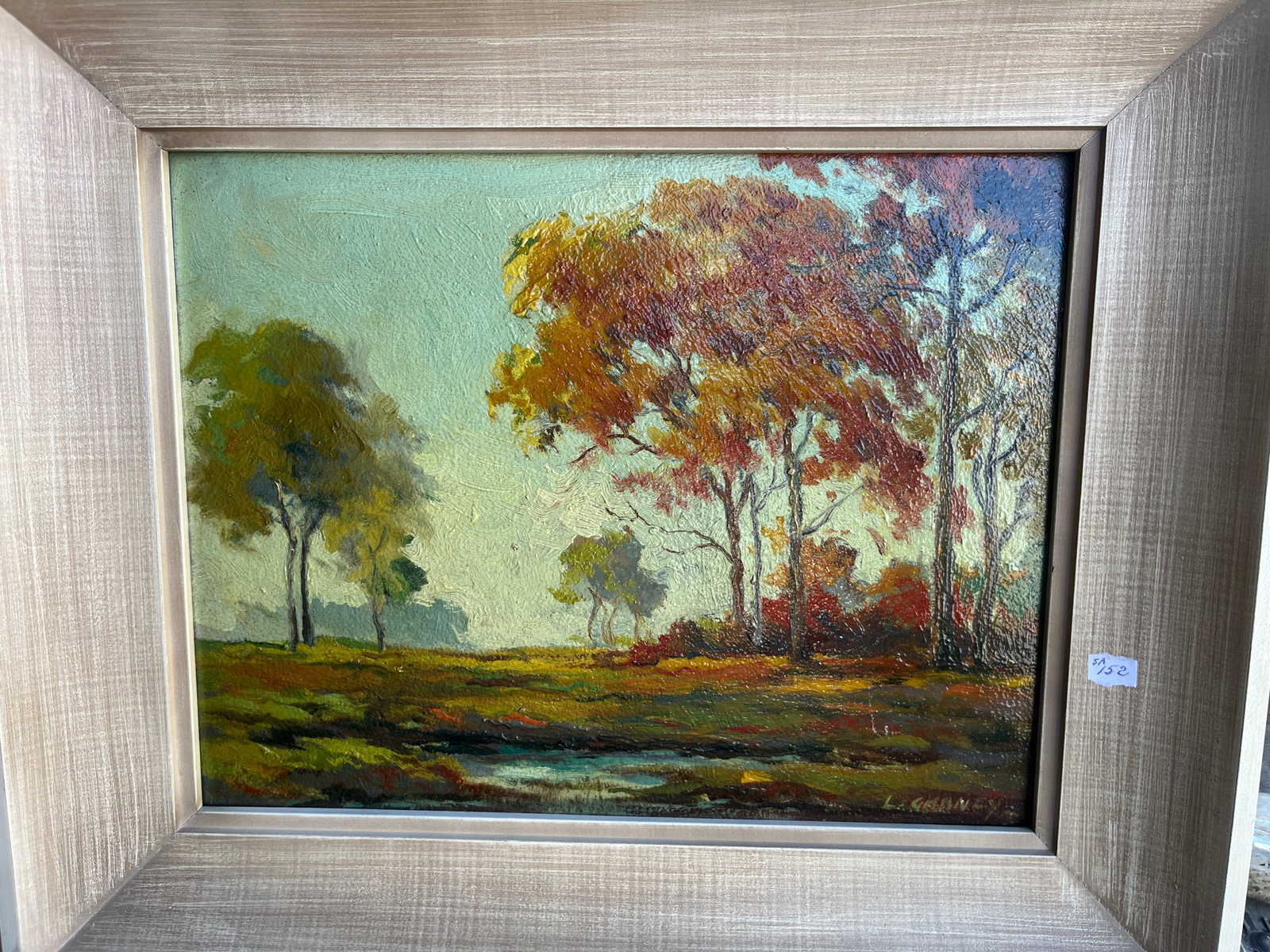 L. Gollner (20th Century) – Autumn Landscape: 11x14. A tranquil impressionist-style landscape depicting trees in warm autumn tones beside a reflective pond. The artist’s expressive brushwork and layered impasto create a luminous atmosphere,