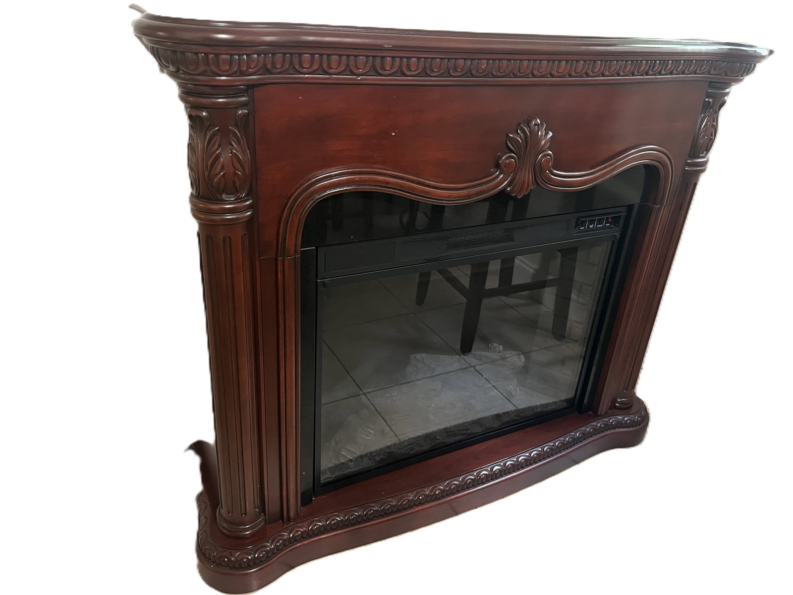 Twin Star Electric Fireplace with Carved Mahogany Mantel: Elegant Twin Star electric fireplace insert (Model#33EF010GRA) housed in a richly carved mahogany finish wood mantel (Model#67183). The mantel features classical scroll and leaf motifs with fluted col