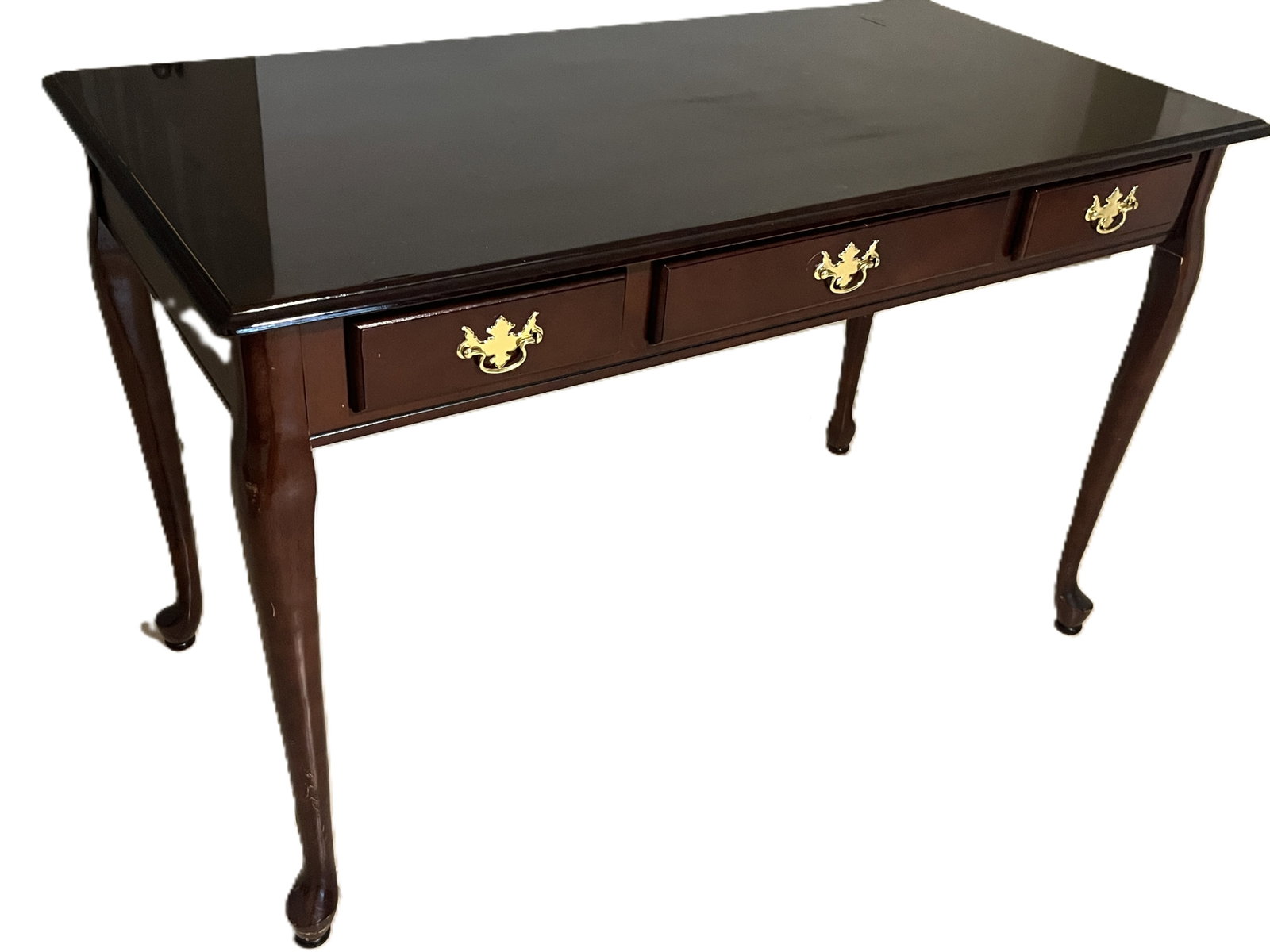 Queen Anne Style Mahogany Writing Table with Brass Hardware: Elegant mahogany writing table in the Queen Anne style, featuring a high-gloss finish and three felt-lined drawers with ornate brass batwing pulls. The table stands on graceful cabriole legs ending in