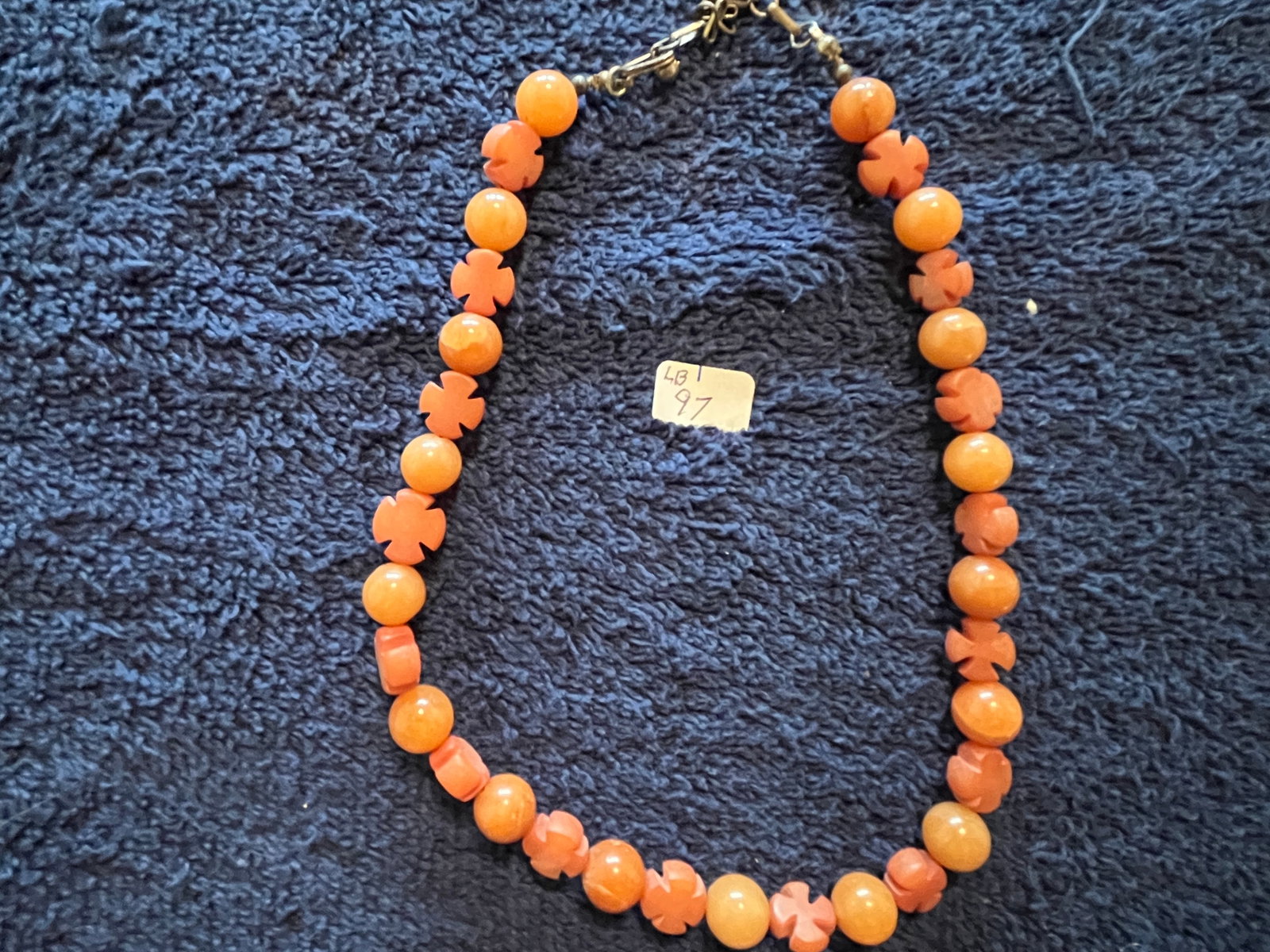 Vintage Bakelite Necklace with Round and Cross Form Orange Beads: A vintage Bakelite necklace featuring alternating smooth round beads and cross?form beads in warm amber?orange tones. The beads display the characteristic glossy finish and weight of authentic Bakelit