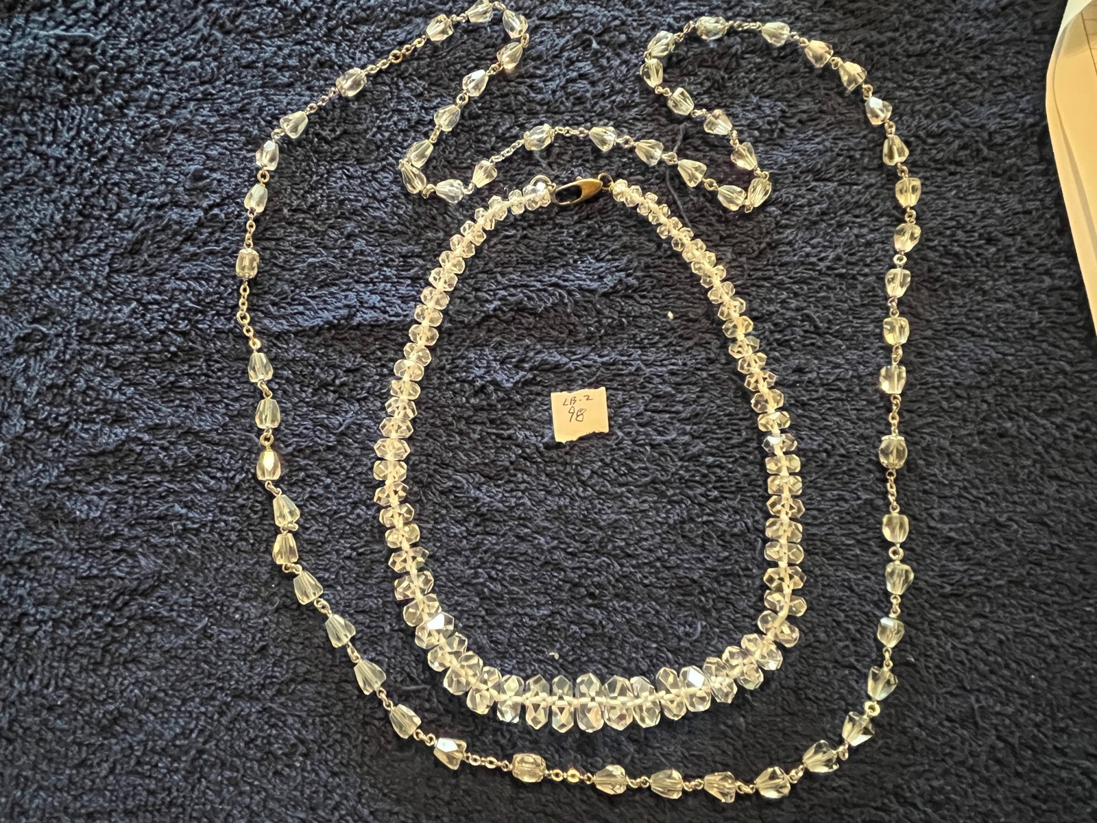 Pair of Vintage Clear Crystal Cut Bead Necklaces Unusual Faceted Forms: A pair of vintage clear crystal cut bead necklaces, each showcasing distinctive mid century bead craftsmanship. The shorter strand features deeply double faceted bicone crystals, cut with sharp angula