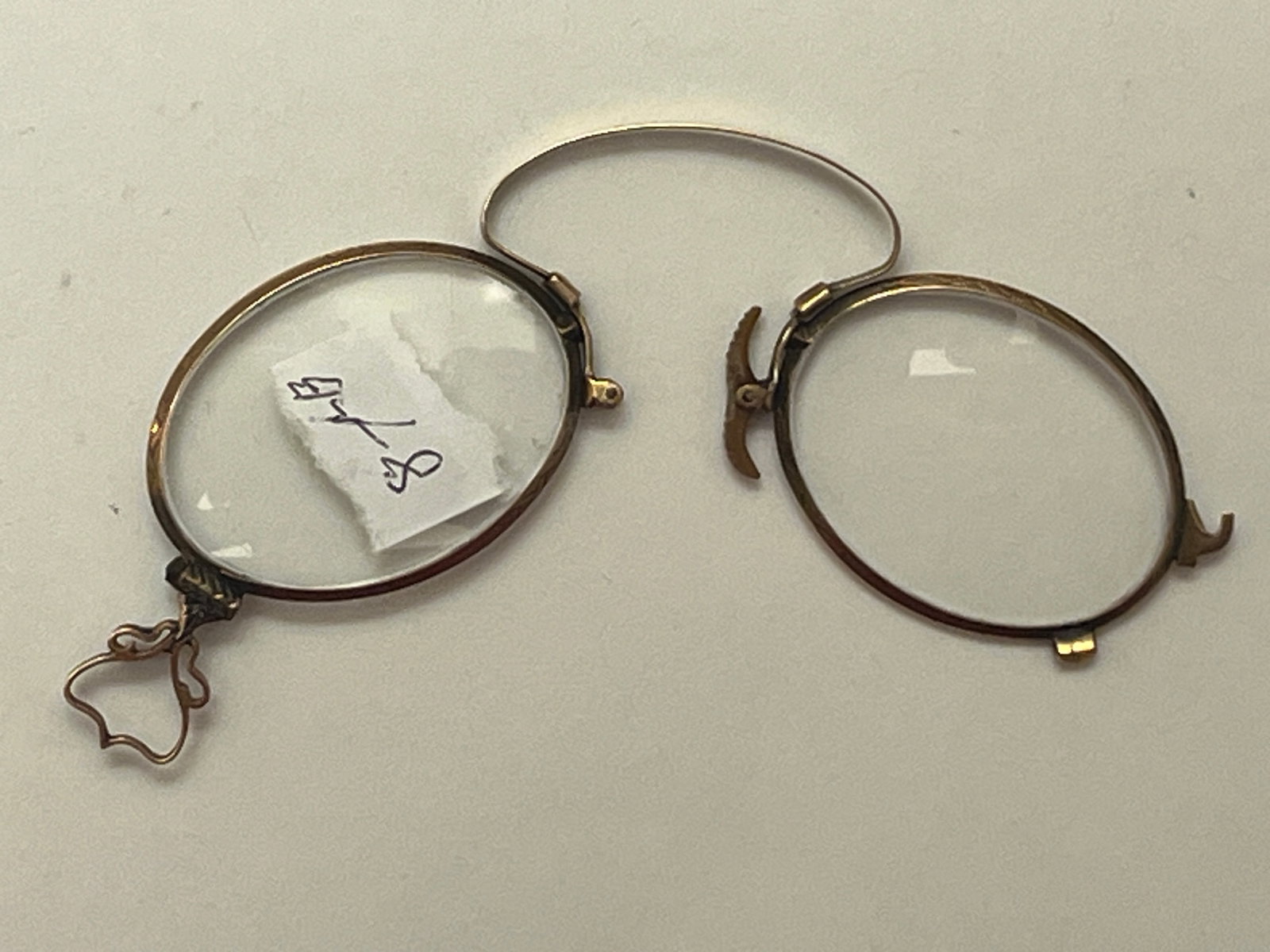 Antique Folding Pince-Nez Eyeglasses with Finger Ring, Late 19th/Early 20th C.: Antique folding pince-nez eyeglasses dating to the late Victorian or Edwardian period, featuring oval lenses in a gold-tone metal frame with spring bridge and decorative finger ring loop for carrying 