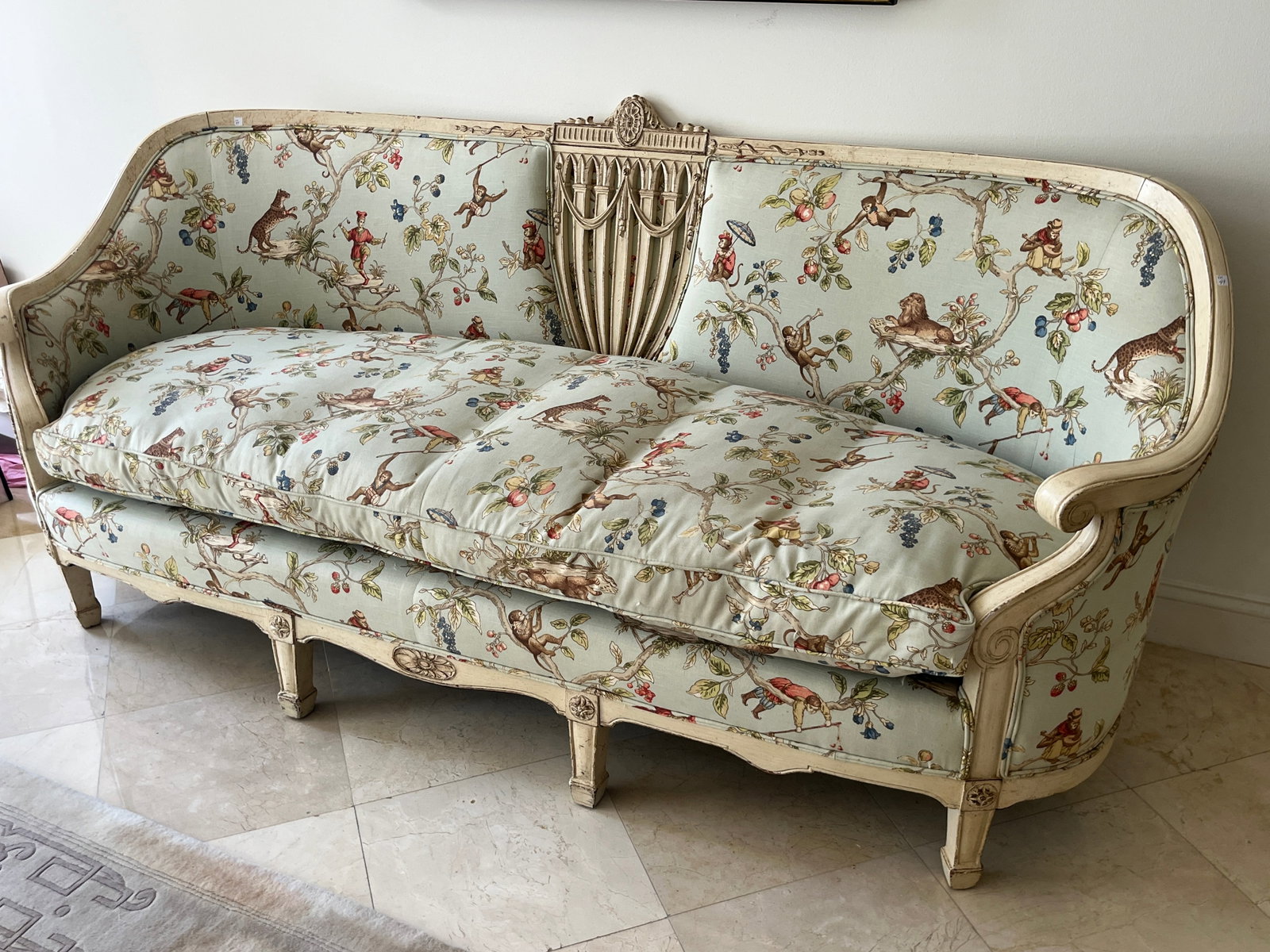 Louis XVI Style Painted Settee with Chinoiserie Animal Upholstery, Provenance: Amy Whittlesey: An exceptional Louis XVI–style carved and painted settee featuring a cream-toned frame with fluted legs, rosettes, and draped crest detail. Upholstered in whimsical Chinoiserie inspired fabric depic