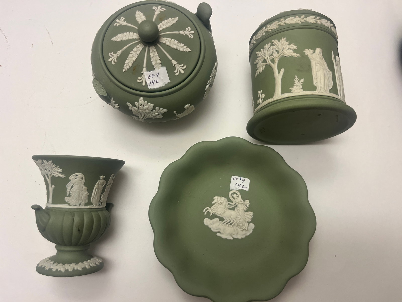Four Wedgwood Sage Green Jasperware Decorative Accessories: Collection of four (4) Wedgwood sage green jasperware decorative pieces with applied white neoclassical relief decoration. The lot includes a covered teapot or sugar bowl, a covered cylindrical tobacc