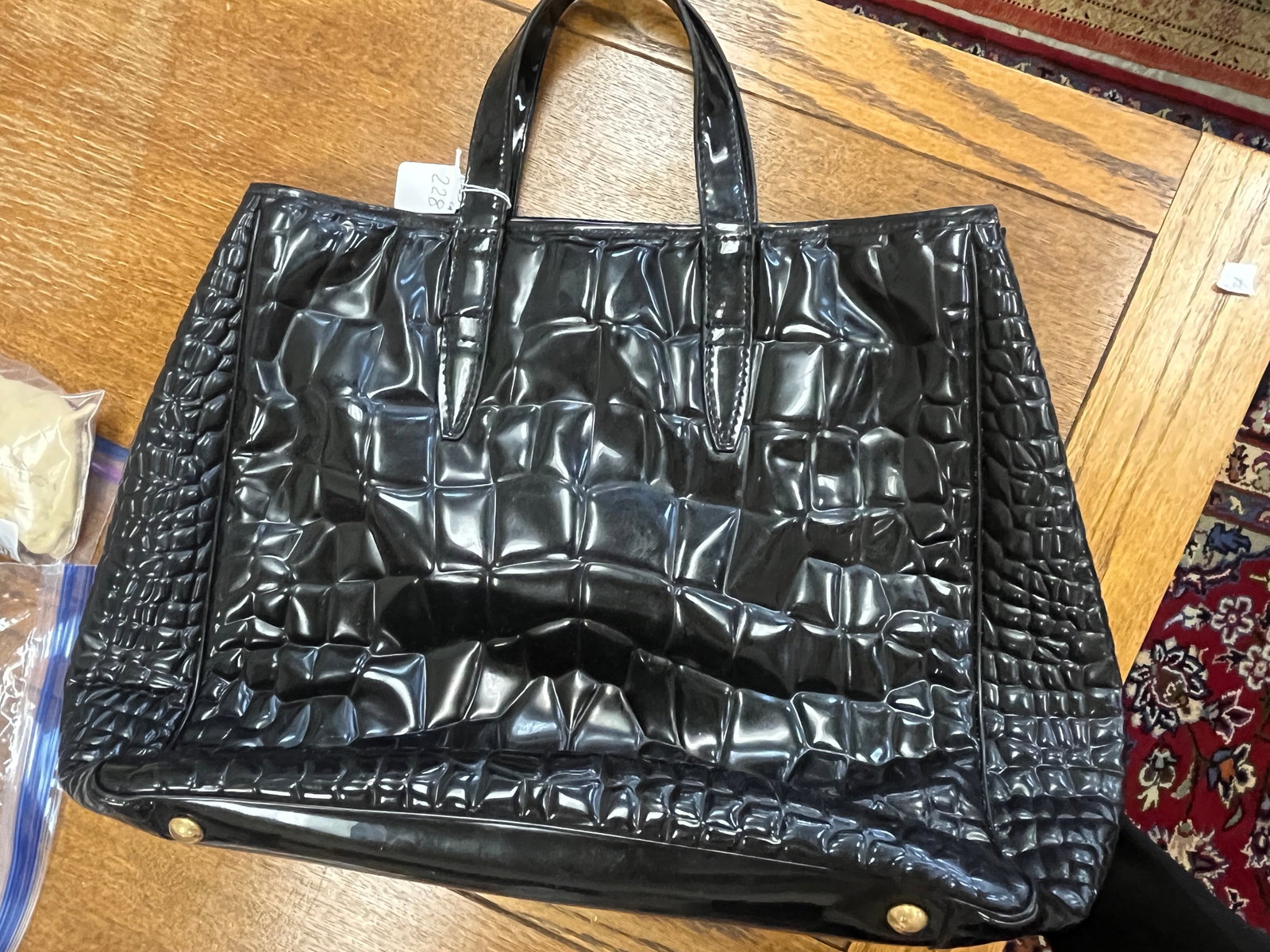 YVES SAINT LAURENT?STYLE FAUX PATENT LEATHER HANDBAG ? 12?H ??16?W ??5?D: Black faux patent leather handbag in the Yves Saint Laurent style, featuring crocodile?embossed texture, dual top handles, and gold?tone hardware feet. Interior lined in black fabric with imitation ?Y
