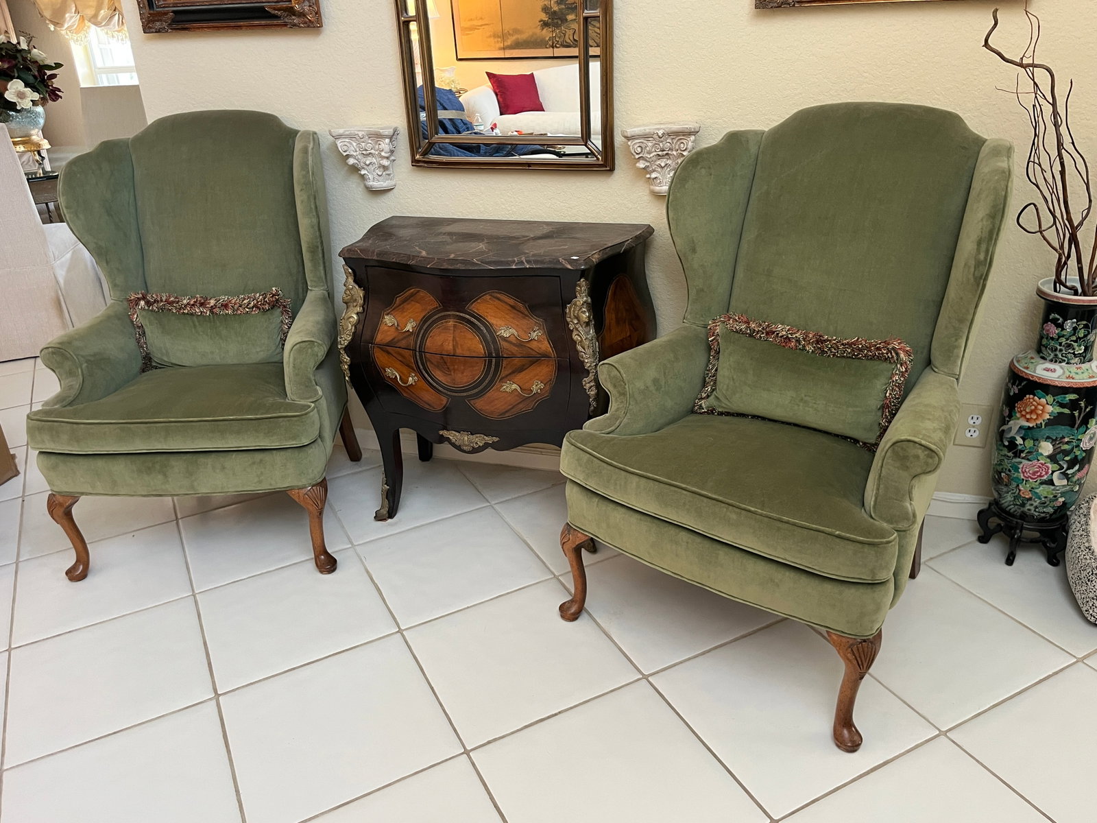 Pair Traditional Queen Anne Style Green Velvet Wingback Armchairs ? Carved Cabriole Legs: Handsome pair of traditional wingback armchairs upholstered in a soft sage/olive green velvet. Each chair features a tall shaped back with pronounced wings, rolled arms, loose upholstered seat cushion