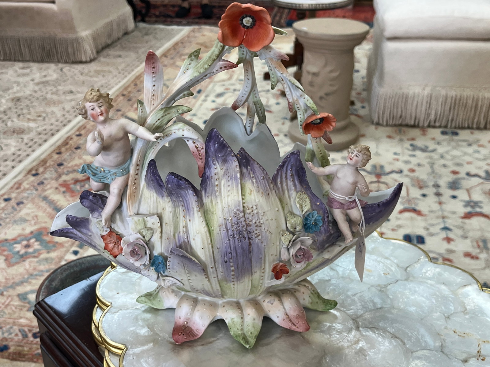VTG Bisque Porcelain Cherub & Floral Figural Basket with Gilt Accents ? 11" x 12" x 7": Elaborate vintage bisque porcelain decorative basket featuring two dimensional cherub figures surrounded by large sculptural leaves, applied flowers and tall flowering stems. Hand-painted in soft lave