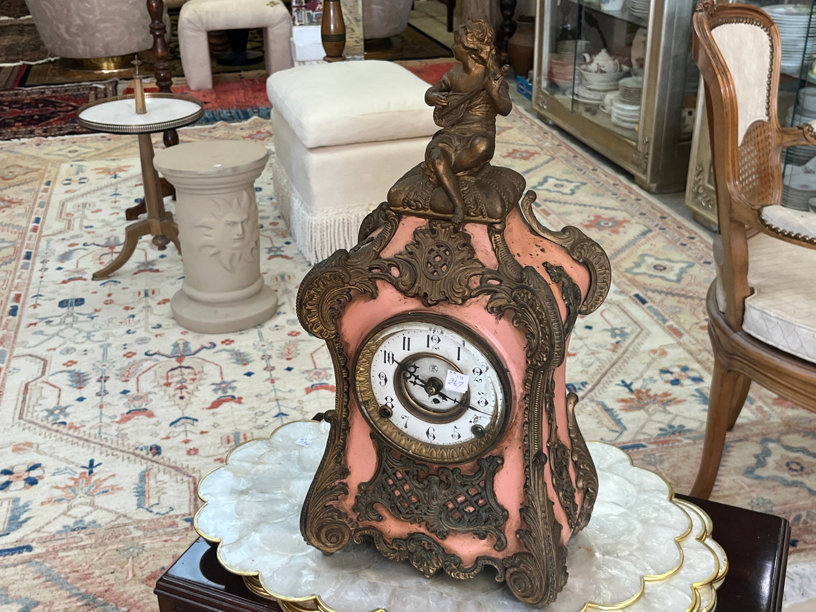 VTG Ornate Figural Mantel Clock w/ Musician Finial ? 19" H x 9.5" W x 5" D: Elaborate vintage European-style mantel clock featuring a pink painted case heavily decorated with ornate bronze-tone metal mounts, pierced latticework, scrolling foliate decoration and a prominent se