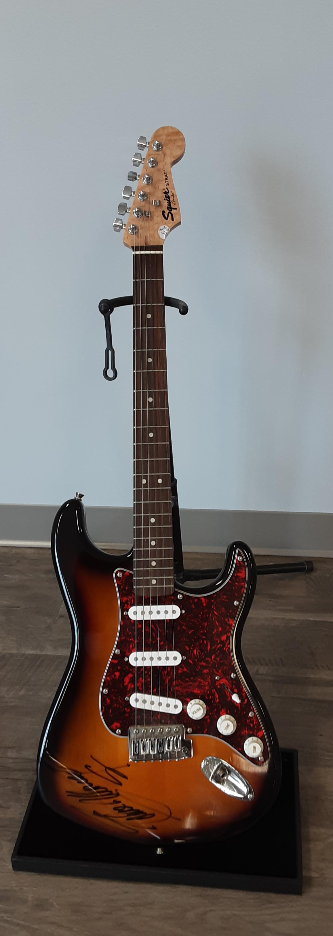Electric guitar, autographed by Eddie Money: Stunning fender Squier sunburst electric guitar, Strat model. Hand signed and autographed by Eddie Money. Hit songs like Baby hold on, Maybe I’m a fool. A highlight to your collection.