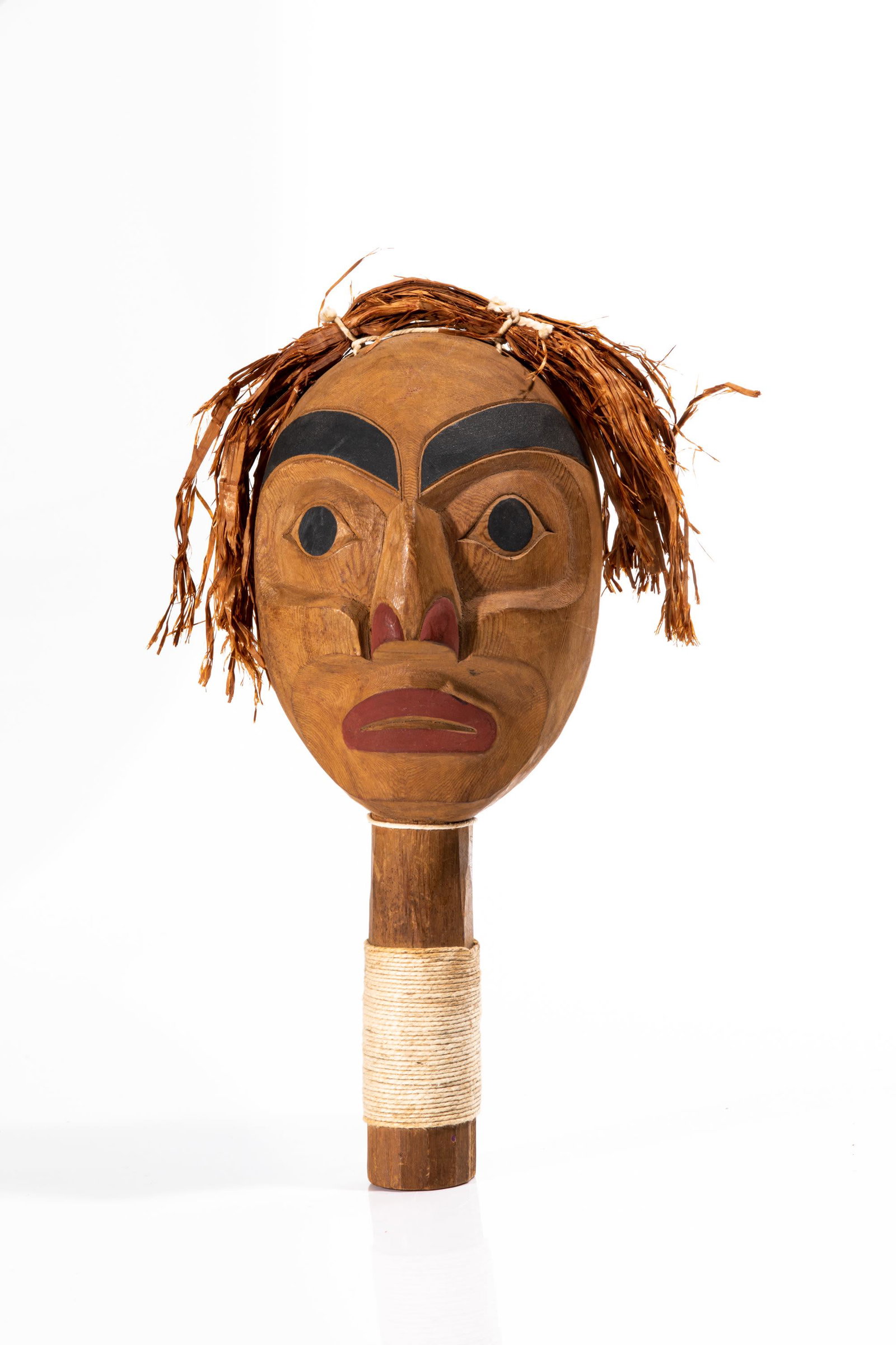 UNIDENTIFIED MAKER, HAIDA, Rattle: UNIDENTIFIED MAKER, HAIDA Rattle carved in low relief and painted with stylized countenance of a human face, with cedar bark attachments representing hair, and string thongs wrapping the han