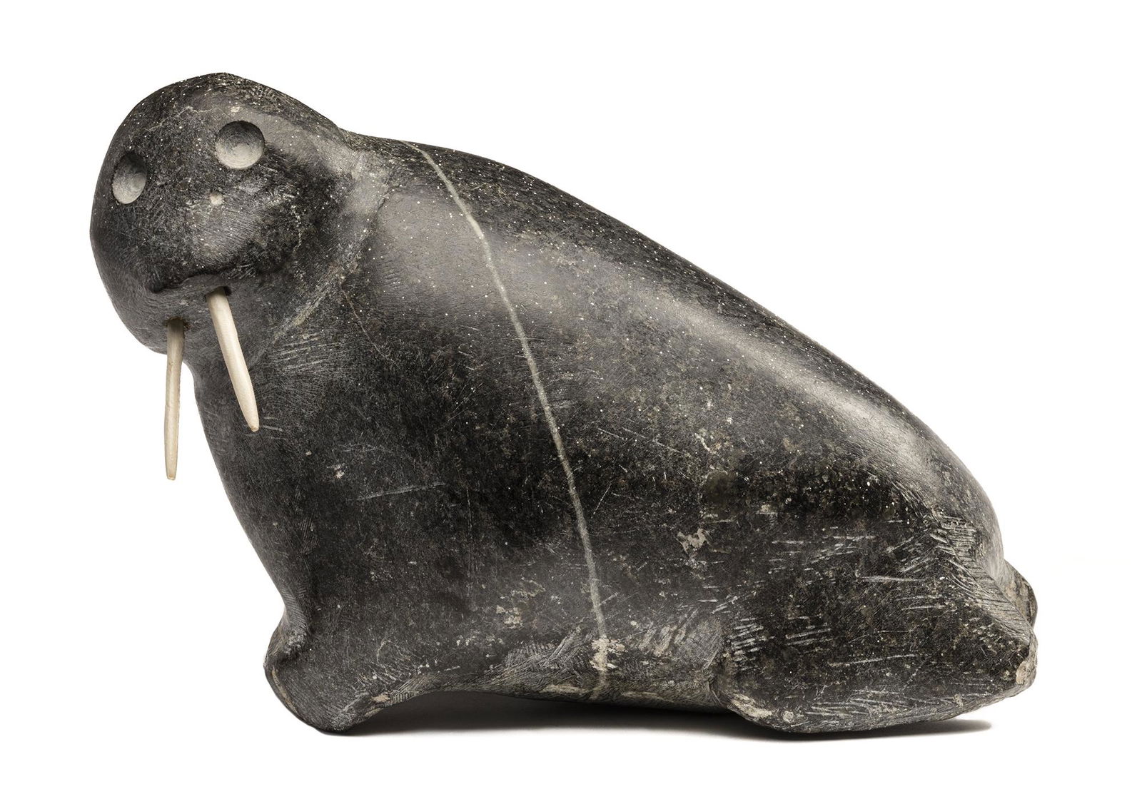 JOHN KAVIK, Inuit, Walrus, c. early-mid 1970s: JOHN KAVIK (1897-1993) KANGIQLINIQ (RANKIN INLET) Walrus,c. early-mid 1970s stone and walrus tusk, 5.75 x 4 x 8 in (14.6 x 10.2 x 20.3 cm) signed, “ᑲᕕ”. Provenance Priv