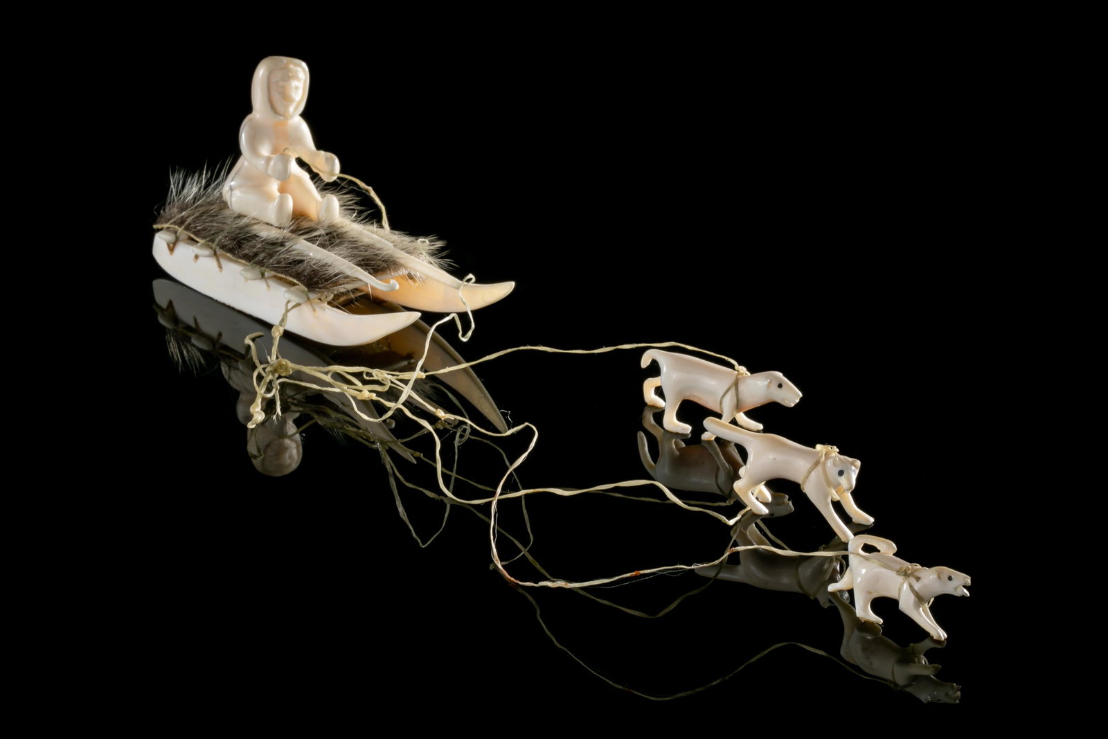 UNIDENTIFIED, INUIT, Hunter on Sled & Dogs, c. 1980: UNIDENTIFIED INUIT ARTIST, EASTERN CANADIAN ARCTIC Hunter on Qamutiq (Sled) with Qimmiit (Sled Dogs), c. 1980 walrus tusk, sinew, and seal skin, dimensions variable: 2.25 x 12 x 2.5 in (5.7 x 30.5 x 6