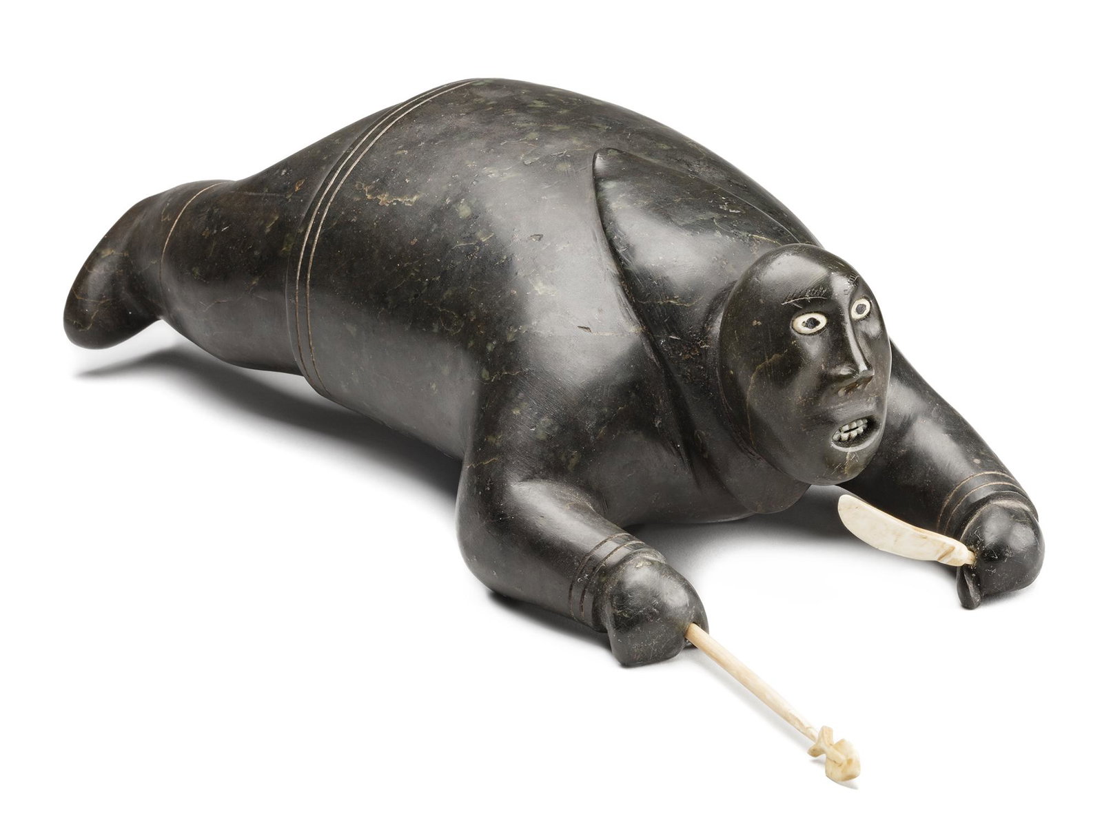 Attr: JOHNNY INUKPUK, INUIT Crawling Hunter, c. 1952: Attributed to JOHNNY INUKPUK, R.C.A (1911-2007) INUKJUAK (PORT HARRISON) Crawling Hunter with Knife and Spear, c. 1952 stone, walrus tusk, and soap inlay, 4 x 12.25 x 6 in (10.2 x 31.1 x 15.2 cm), mea