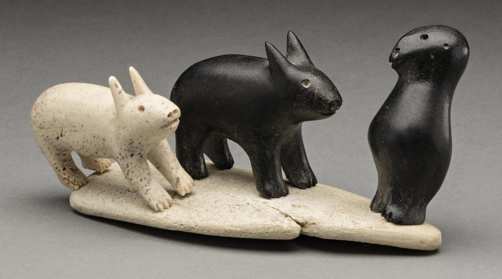 KIASIHA (?), INUIT, Arctic Hares and Owl on Base, c. mid-late 1960s: KIASIHA (?) IKPIARJUK (ARCTIC BAY) Arctic Hares and Owl on Base, c. mid-late 1960s whalebone and stone, 2.5 x 4.5 x 2.75 in (6.3 x 11.4 x 7 cm) signed indistinctly, "KIASIHA (?)". Provenance Private C