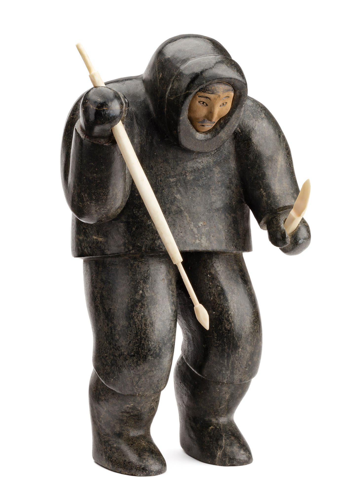 THOMASIE QAMUGAALUK, INUIT, Hunter with Spear and Knife, c. 1954-55: THOMASIE QAMUGAALUK (1917-1995) SALLUIT (SUGLUK) Hunter with Spear and Knife, c. 1954-55 stone, walrus tusk, and graphite, 8 x 4.75 x 5 in (20.3 x 12.1 x 12.7 cm) unsigned. Provenance Important Privat
