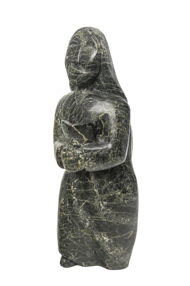 OVILOO TUNNILLIE, INUIT, Woman Holding a Book, early 2000s: OVILOO TUNNILLIE, R.C.A. (1949-2014) KINNGAIT (CAPE DORSET) Woman Holding a Book, early 2000s stone, 15.75 x 5.5 x 3.75 in (40 x 14 x 9.5 cm) signed, inscribed with artist's disc number, and further i