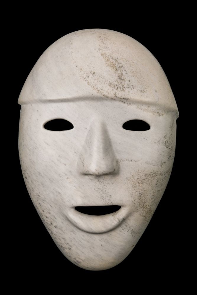 TAQIALUQ NUNA , INUIT, Mask, 1989: TAQIALUQ NUNA (1958-) KINNGAIT (CAPE DORSET) Mask, 1989 stone, 19.5 x 13 x 5 in (49.5 x 33 x 12.7 cm) with etched depiction of a stylized face, verso; signed with artist's stylized signature, signed a