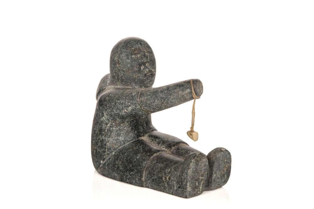 MARY YUUSIPIK SINGAQTI, INUIT, Seated Child Playing a Game, c. early 1980s: MARY YUUSIPIK SINGAQTI (1936-2017) QAMANI’TUAQ (BAKER LAKE) Seated Child Playing a Game, c. early 1980s stone, sinew, and antler, 4.25 x 3 x 4.75 in (10.8 x 7.6 x 12.1 cm) signed, "ᔪᓯ