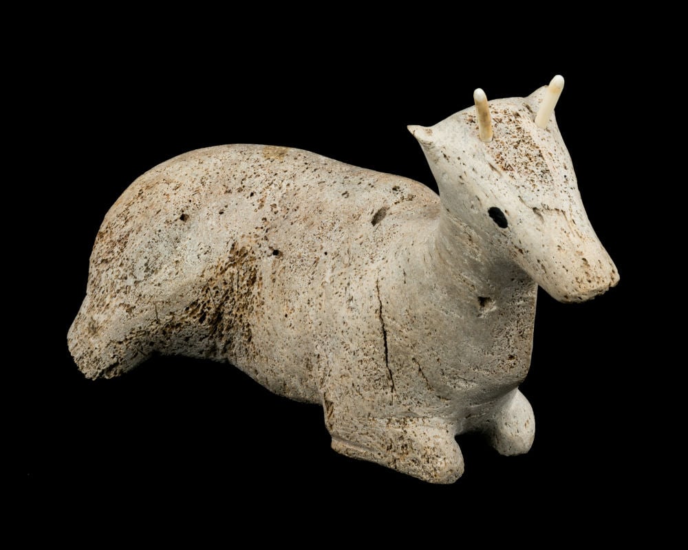 UNIDENTIFIED INUIT ARTIST, Resting Caribou Calf, early 1970s: UNIDENTIFIED INUIT ARTIST, POSSIBLY NAUJAAT (REPULSE BAY) Resting Caribou Calf, early 1970s whale bone, antler, and black in lay, 7 x 12.5 x 3 in (17.8 x 31.8 x 7.6 cm) unsigned. Provenance Private Co