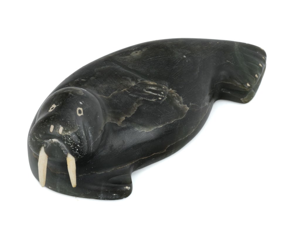 KOMALUK, INUIT, Lounging Walrus, mid-late 1960s: KOMALUK (1938-) INUKJUAK (PORT HARRISON) Lounging Walrus, mid-late 1960s stone and antler, 1.5 x 4.5 x 2.25 in (3.8 x 11.4 x 5.7 cm) signed and inscribed with disc number, "KOOMALOOK / E-4-1684". Prov