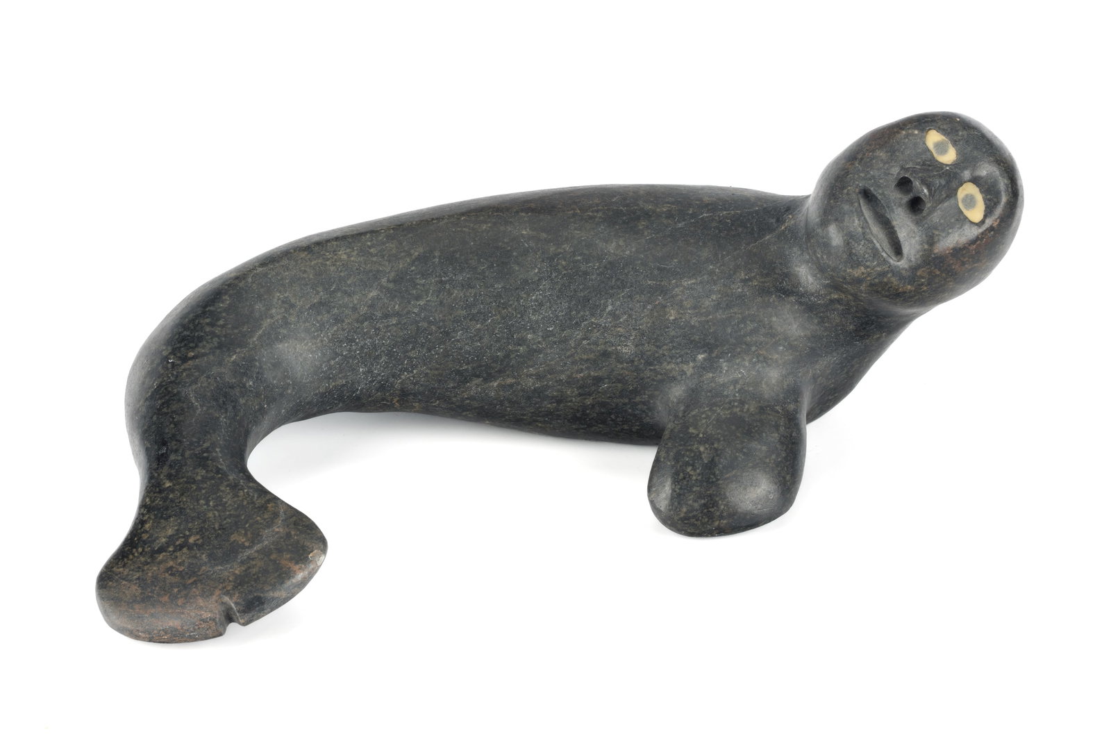 JOSIAH NUILAALIK, INUIT, Seal Shaman, c. 2000: JOSIAH NUILAALIK (1928-2005) QAMANI'TUAQ (BAKER LAKE) Seal Shaman, c. 2000 stone and resin[?] inlay, 5 x 12.25 x 9 in (12.7 x 31.1 x 22.9 cm) signed, "ᓄᐃᓚᓕ". Provenance Collect