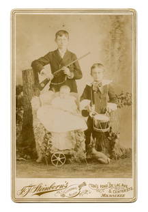 Cabinet Card of 3 Children w/ Gun, Drum, & Horn: Cabinet card taken in Milwaukee, Wisconsin of three children, presumably siblings, carrying a rifle, drum, and horn. Charming family portrait. [Antique photography, Daguerreotype, Ambrotype,