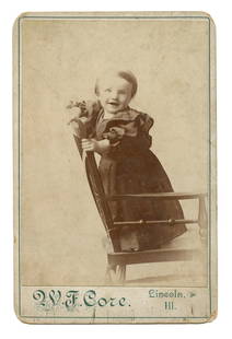 Cabinet Card of Happy Baby: Cabinet card of a happy baby standing on a chair. Mount bears the imprint of a photographer's studio in Lincoln, Illinois. [Antique photography, Snapshot, Stereotype, Daguerreotype, Ambrotype,