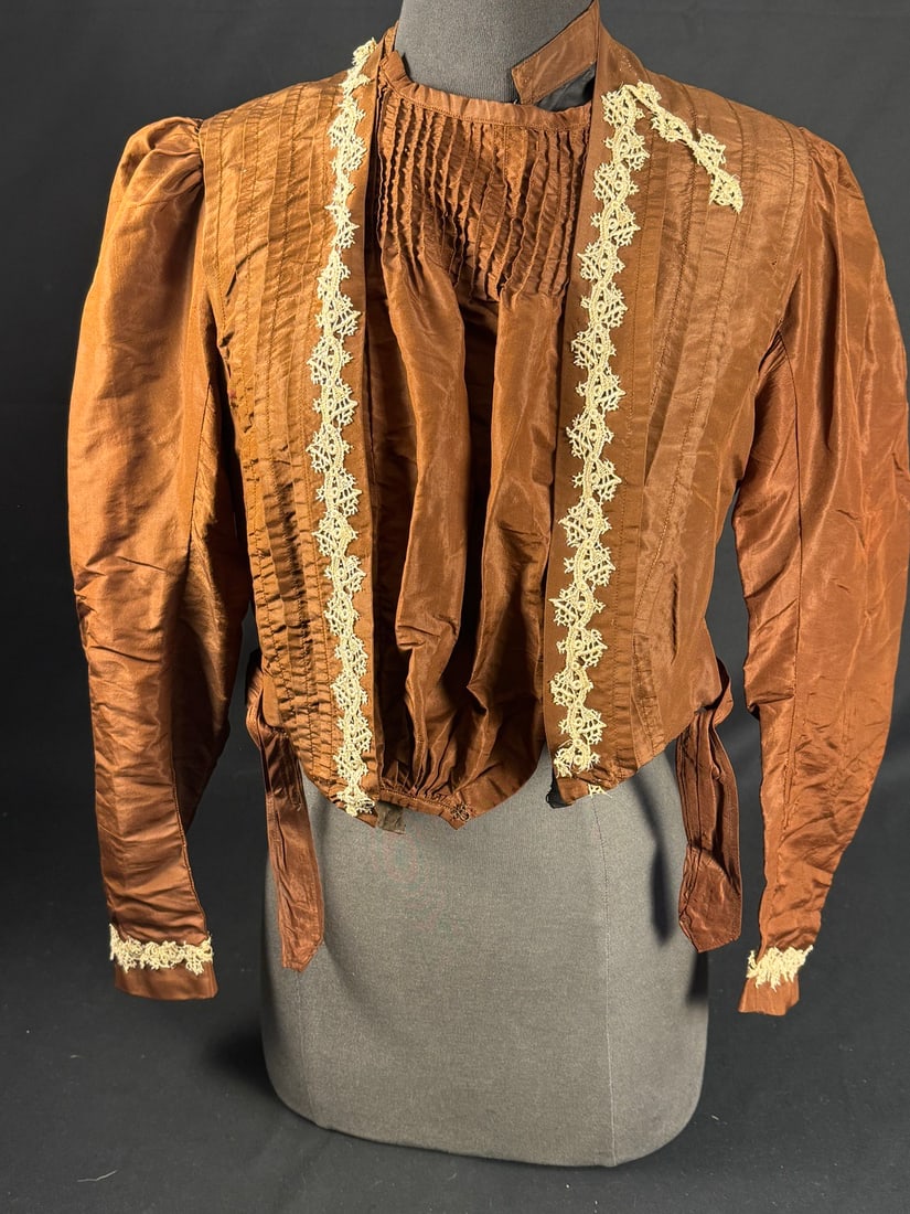 1905 Brown Edwardian Bodice with lace trim: Brown taffeta Edwardian bodice with typical to the period front pleated styling. Cream colored machine lace trim is in very good condition. The lining provides the structure for the bodice and ensures