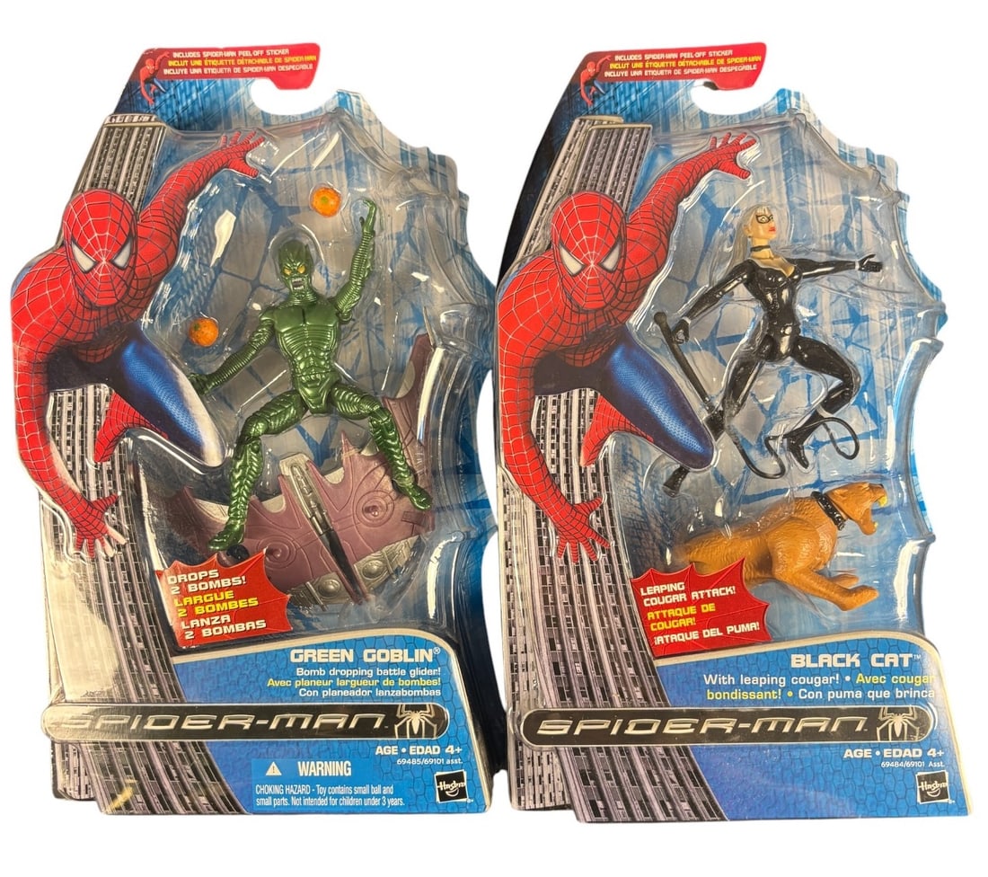 A Pair of Hasbro Spider-man Action Figures: Green Goblin With Bomb Dropping Battle Glider and Black: This lot comprises a pair of Hasbro -SPIDER-MAN- series blister-carded plastic action figure sets. The first set features the character -GREEN GOBLIN- accompanied by a bomb-dropping battle glider and