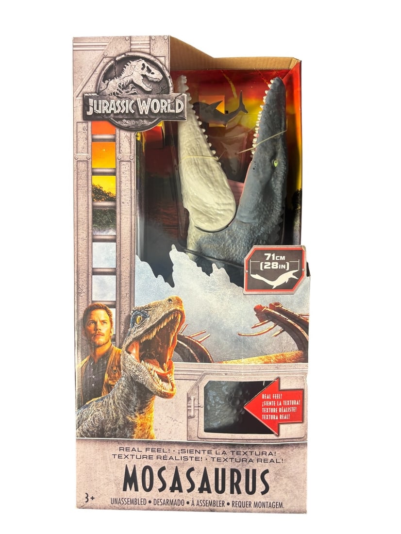 Mattel Jurassic World Real Feel Mosasaurus Action Figure, Boxed: A modern, boxed retail toy from the -JURASSIC WORLD- franchise, featuring a Mattel Real Feel Mosasaurus action figure. The item is presented in a cardboard box with a partial plastic window, revealing