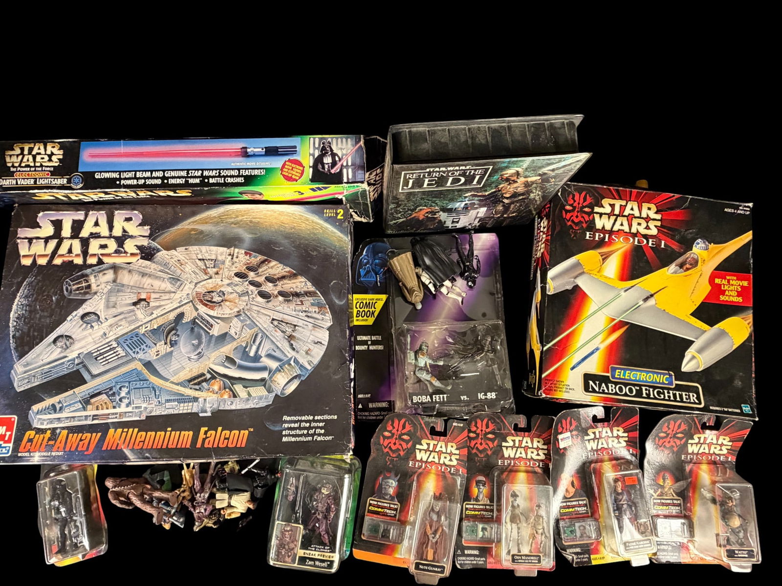 Star Wars Toys and Collectibles Including an AMT Ertl Cut-Away Millennium Falcon Model Kit: A collection of Star Wars themed toys and collectibles primarily from the late 1990s and early 2000s. The group features an AMT Ertl Cut-Away Millennium Falcon model kit, a Hasbro Electronic Naboo Fig