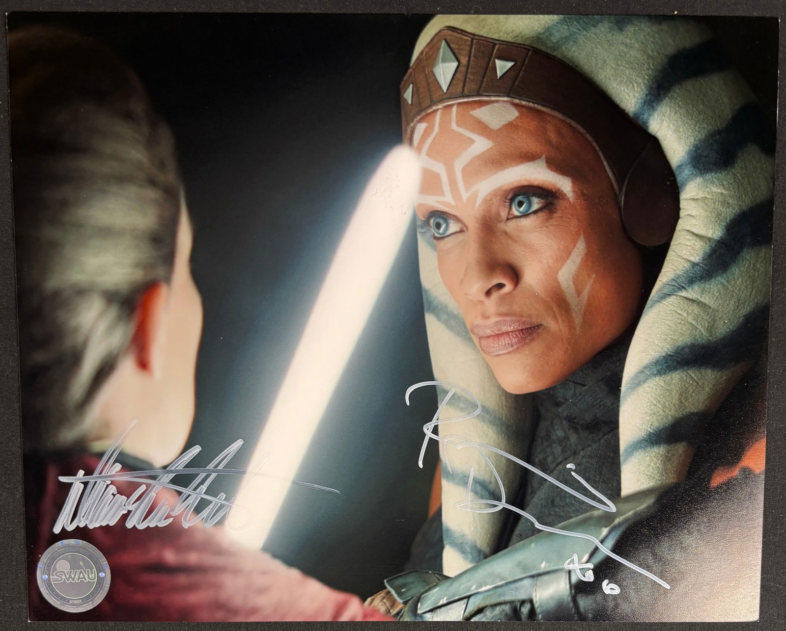 Star Wars: The Mandalorian Dual-Signed Photograph Rosario Dawson and Diana Lee Inosanto SWAU: This professional-grade entertainment memorabilia offering features a high-gloss color photograph from the acclaimed Disney+ Star Wars series, The Mandalorian. The image captures the pivotal confronta