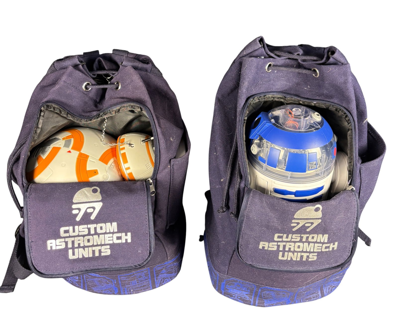 A Pair of Disney Star Wars Galaxy s Edge Droid Depot Custom Astromech Backpacks with Droids: A pair of Disney Star Wars Galaxys Edge Droid Depot Custom Astromech Backpacks. Each backpack is constructed from navy blue canvas and features a drawstring top closure, adjustable shoulder straps,