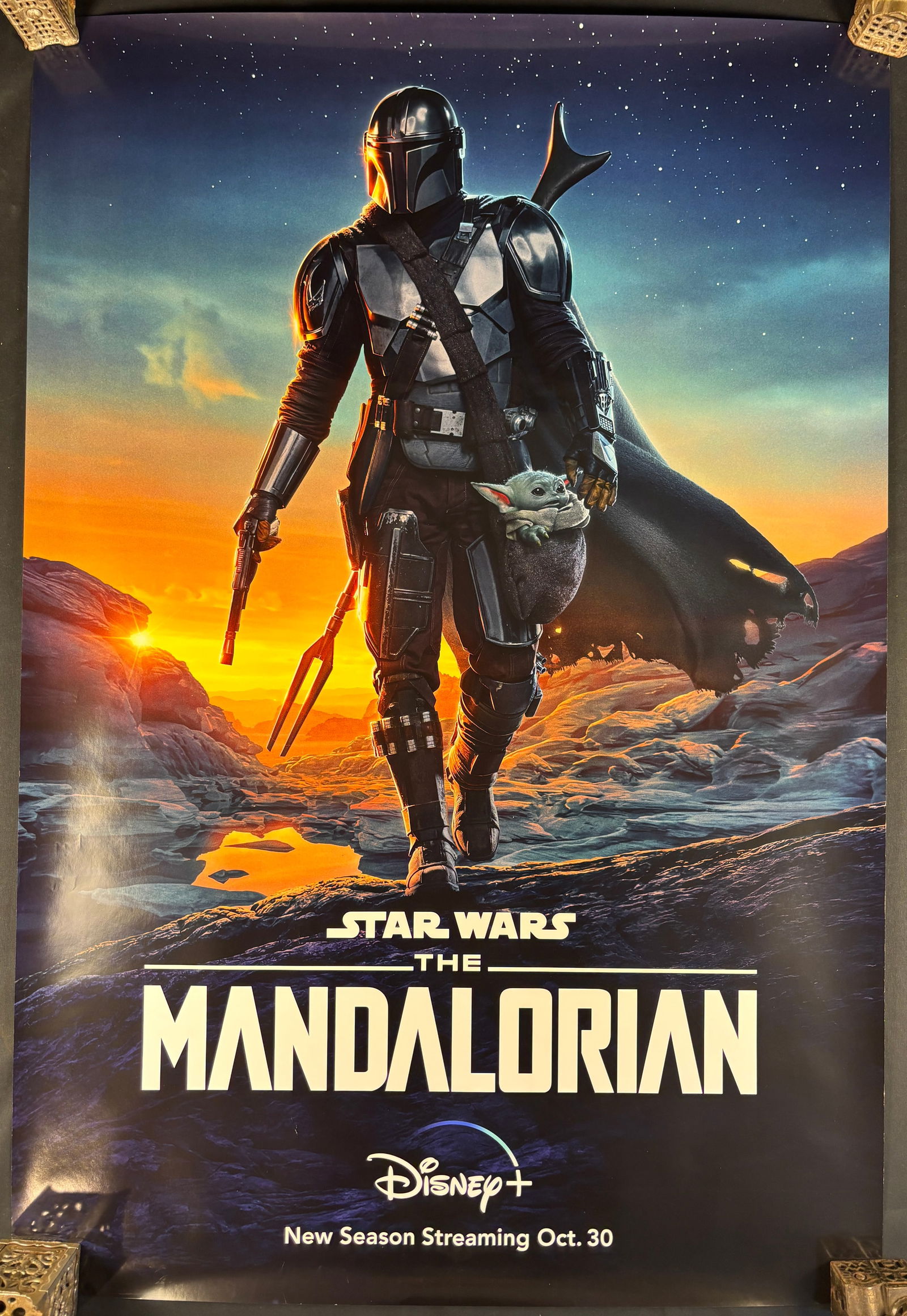 Star Wars: The Mandalorian Season Two Disney+ Promotional Poster: A vertical promotional poster for the Disney+ series Star Wars: The Mandalorian, specifically advertising the second season. The graphic features the central protagonist in silver-toned armor